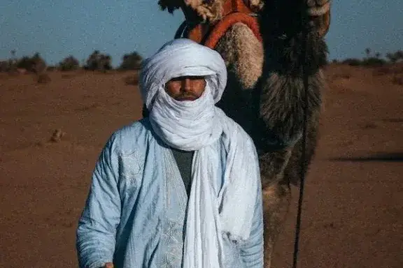 Guía junto a un camello cargado