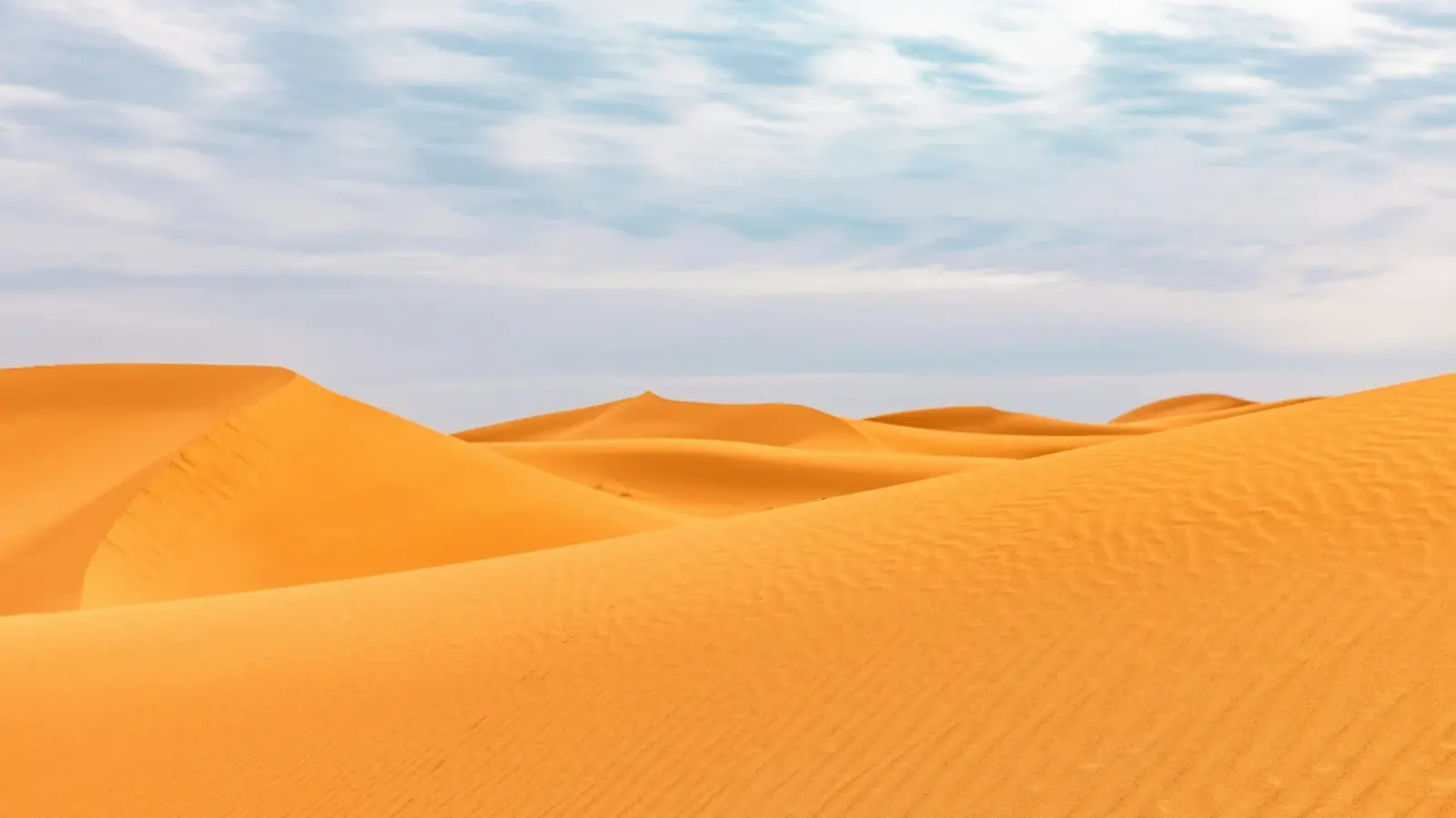 Dunes dorées d’Erg Chigaga et fines rides de sable sous un ciel nuageux