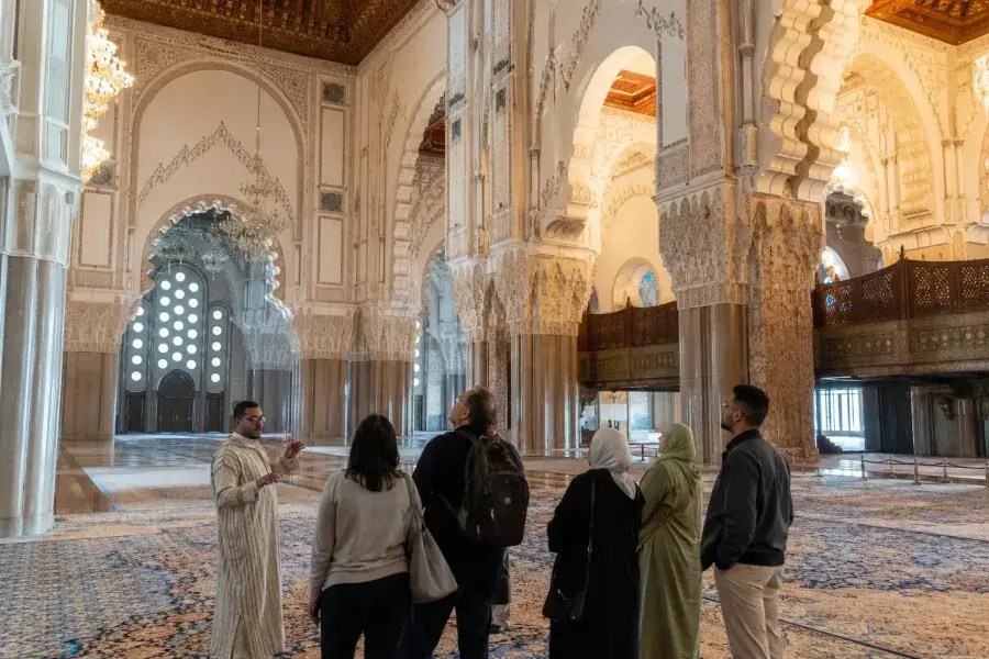 Visitantes descubriendo el detallado interior de la mezquita Hassan II en Casablanca