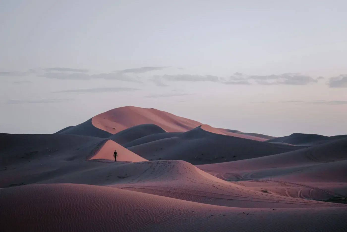 Lone walker among dunes at Erg Chigaga near sunset