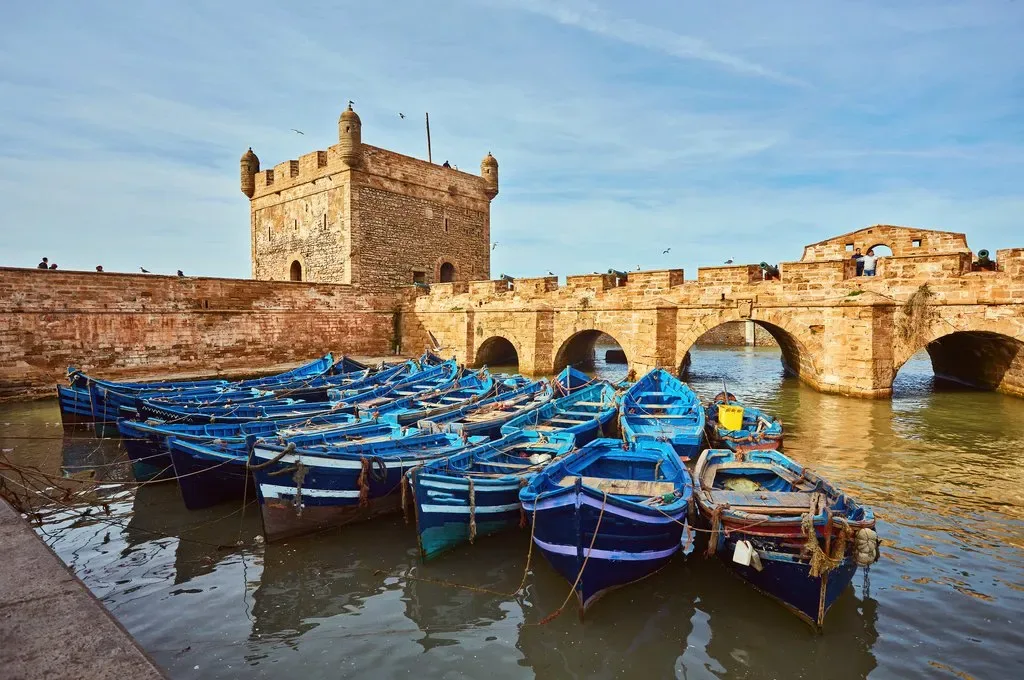 Blue fishing boats beside the historic port walls in Essaouira on Morocco's Atlantic coast