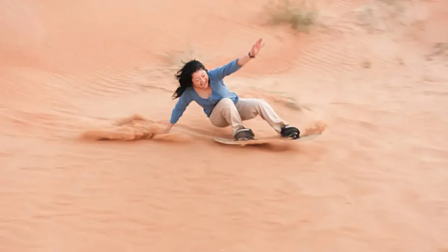 Traveler sandboarding on an Erg Chebbi dune near Merzouga