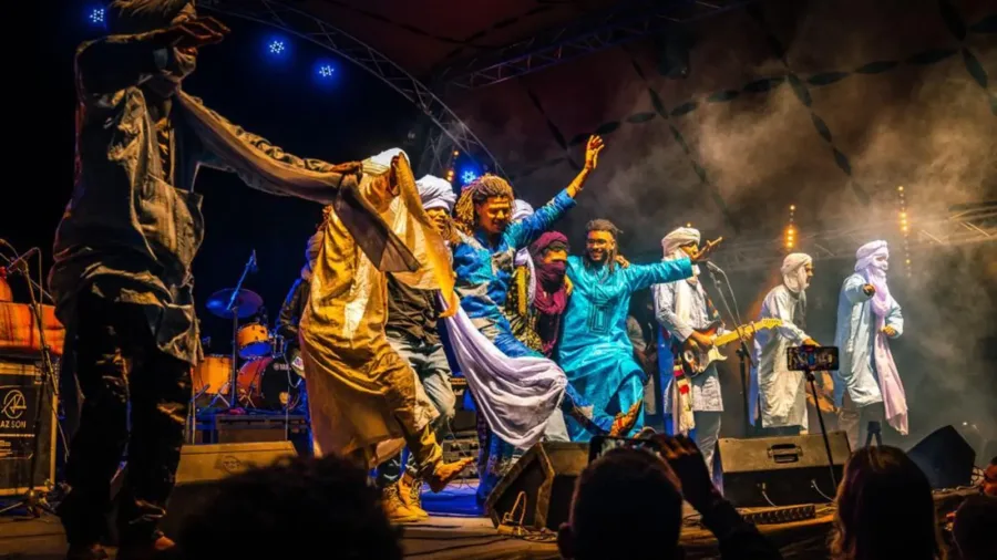 Sahraoui musicians playing hand drums beside a desert campfire
