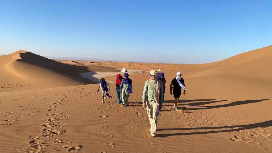 Travelers walking across the Sahara with a Sahraoui desert guide