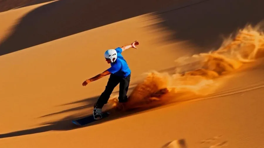 Traveler sandboarding on a tall Erg Chigaga dune